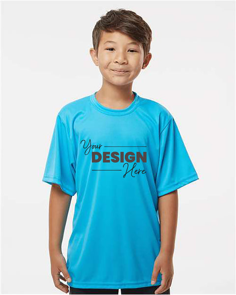 A young boy is standing, wearing a blue C2 Sport Youth Performance T-Shirt by C2 Sport, with the text 