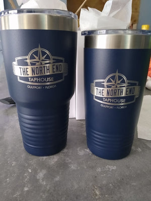 Two blue insulated tumblers on a table, both featuring the logo and name "The North End Taphouse, Gulfport - Florida." The taller laser engraved tumbler is on the left and the shorter on the right. These are Custom Tumblers 20 oz with your Logo or Design Engraved - Special Bulk Wholesale Pricing - Pack of 12 Pieces - 1 Color by Kodiak Coolers.