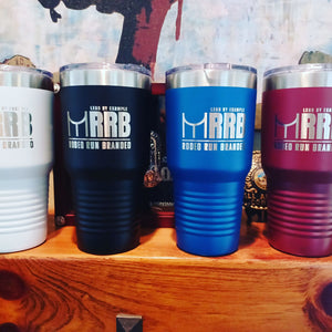 Four Custom Tumblers 20 oz with your Logo or Design Engraved - Special Bulk Wholesale Pricing - Pack of 12 Pieces - 1 Color by Kodiak Coolers in white, black, blue, and maroon are lined up on a wooden surface. Background includes medals or awards partly visible.