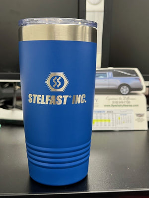 A blue stainless steel travel mug, laser engraved with "STELFAST INC.," sits on a black desk. In the background, there is a business card holder with cards and a picture of a car. Custom Tumblers 20 oz with your Logo or Design Engraved - Special Bulk Wholesale Pricing - Pack of 24 Pieces - 1 Color - $14.85 Each like this one are available at wholesale pricing for businesses from Kodiak Coolers.