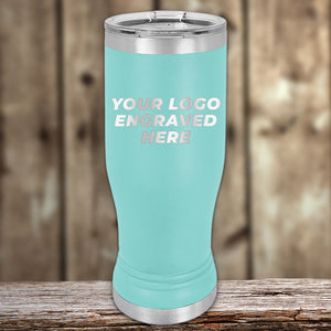 A teal stainless steel tumbler with a lid, standing on a wooden surface. The text on the tumbler reads "Your Engraved Logo Here." The background is a blurred wooden texture. Ideal for those looking into bulk wholesale pricing for Custom Pilsner Tumblers 14 oz with your Logo or Design Engraved by Kodiak Coolers | No Minimal Order | Sample Volume Pricing.