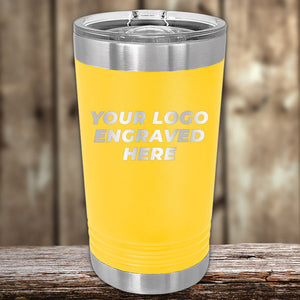 Yellow insulated tumbler with stainless steel top and bottom, featuring the words "4th of July SALE - Engraved Custom Logo Drinkware - Front Engraved Logo Included - $250 Minimal Order - Product Styles 3" by Kodiak Coolers. This custom drinkware piece is placed on a rustic wooden surface with a blurred wooden background. Perfect for personalized promotional gifts.