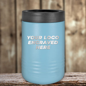 A blue insulated Kodiak Coolers tumbler with a black lid, featuring "Your Logo Engraved Here," rests on a wooden surface. This custom laser-etched design is the perfect corporate promotional gift. Limited time offer, no setup fees!.