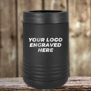 The black Custom Tumbler by Kodiak Coolers, featuring a laser-etched "Your Logo Engraved Here" design, sits elegantly on a wooden surface against a blurred wood background—ideal as a corporate promotional gift.