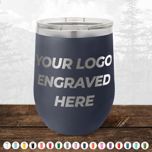 A navy blue tumbler with the text "4th of July SALE - Engraved Custom Logo Drinkware - Front Engraved Logo Included - $250 Minimal Order" by Kodiak Coolers against a blurred outdoor background. Various color options are displayed below the tumbler, making it ideal for promotional gifts and personalized mugs for any occasion.