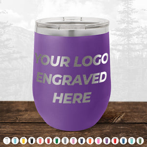 A purple insulated tumbler with "4th of July SALE - Engraved Custom Logo Drinkware - Front Engraved Logo Included - $250 Minimal Order" text on it. Placed on a wooden surface with a backdrop of trees and mountains, it offers an ideal setting for personalized mugs. Various color options are displayed below, making it perfect for promotional gifts from Kodiak Coolers.