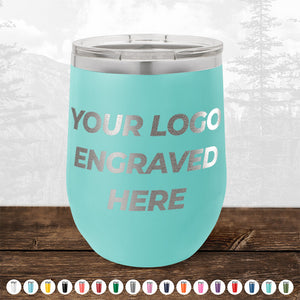 A turquoise tumbler with "Your Logo Engraved Here" text. A variety of color options is displayed below the tumbler, along with a background of mountains and trees. Perfect for 4th of July SALE - Engraved Custom Logo Drinkware - Front Engraved Logo Included - $250 Minimal Order from Kodiak Coolers, making it an ideal choice for promotional gifts.