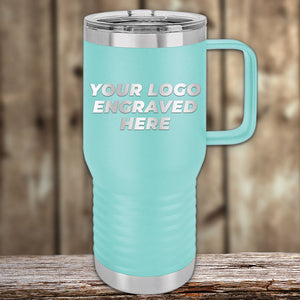 A teal insulated travel mug with a silver lid and handle sits on a wooden surface. Perfect as a corporate gift, the Kodiak Coolers tumbler elegantly displays "YOUR LOGO ENGRAVED HERE" in laser-etched design with no setup fees.