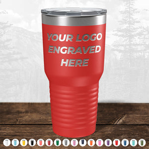 A red insulated tumbler from Kodiak Coolers, showcasing the text "YOUR LOGO ENGRAVED HERE." Available in various colors, this Custom Drinkware Engraved with your Logo or Design makes an ideal promotional gift. The background features a serene forest landscape. Don't miss out on the HUGE LABOR DAY SALE - ENDS TODAY!