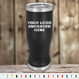 A black stainless steel Custom Pilsner Tumbler 14 oz with the text "YOUR LOGO ENGRAVED HERE" standing on a wooden surface. Various color options for the tumbler are shown below. Enjoy bulk wholesale pricing with every purchase of Kodiak Coolers products including Custom Pilsner Tumblers 14 oz with your Logo or Design Engraved | No Minimal Order | Sample Volume Pricing.