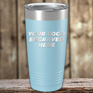 A Kodiak Coolers Custom Tumblers 20 oz with your Logo or Design Engraved - Special Bulk Wholesale Pricing - Pack of 96 Pieces - 1 Color - $13.53 Each, with a light blue exterior and the words "YOUR LOGO ENGRAVED HERE" laser engraved on it, placed on a wooden surface with a blurred wooden background. Perfect for wholesale custom tumblers or bulk orders.