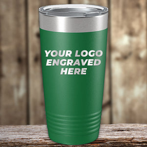 A green travel tumbler with a silver lid is placed on a wooden surface. The tumbler has the text "YOUR LOGO ENGRAVED HERE" printed in white, showcasing laser engraved precision. Ideal for those looking for Kodiak Coolers Custom Tumblers 20 oz with your Logo or Design Engraved - Special Bulk Wholesale Pricing - Bundle Packs.