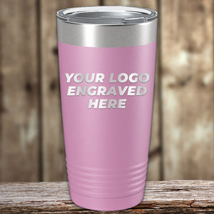 A pink **Kodiak Coolers Custom Tumbler 20 oz with your Logo or Design Engraved - Special Bulk Wholesale Pricing - Bundle Packs** with a silver lid and the text "Your Logo Engraved Here" beautifully laser engraved on the front. The custom tumbler is placed on a wooden surface with a blurred wooden background, perfect for those seeking wholesale pricing.