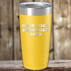 A yellow travel tumbler with a metal rim, shown on a wooden surface, features "YOUR LOGO ENGRAVED HERE" on the front. Perfect for bulk orders, these Kodiak Coolers Custom Tumblers 20 oz with your Logo or Design Engraved - Special Bulk Wholesale Pricing - Bundle Packs are ideal for branding and promotional needs.