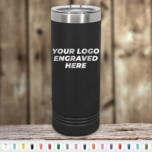 A black Kodiak Coolers tumbler, featuring the text "Your Logo Engraved Here," is set against a wooden background. Below it are rows of colorful custom tumblers, ideal for corporate gifts. Order these laser-etched designs with no setup fees during this limited-time offer.