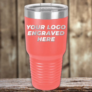 A red insulated Custom Tumblers 30 oz with your Logo or Design Engraved, placed on a wooden surface. The tumbler by Kodiak Coolers has "YOUR LOGO ENGRAVED HERE" meticulously printed on it, making it perfect for promotional items.