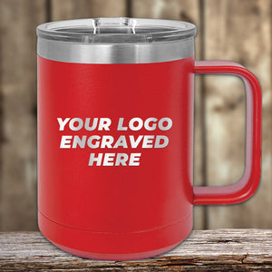 A red insulated mug with a handle and clear lid, displaying the text "Your Logo Engraved Here" on a wooden surface with a blurred wooden background—perfect for custom mugs or as a personalized promotional gift. This Kodiak Coolers product, the Engraved Custom Logo Drinkware - SPECIAL 72 HOUR SALE PRICING - includes single side engraving in the price.