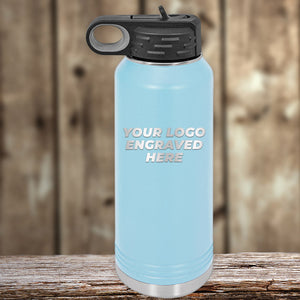 A light blue Kodiak Coolers insulated water bottle with a black lid and carrying handle is placed on a wooden surface. "Your Logo Engraved Here" is printed on the front, making it an ideal promotional gift. This high-quality drinkware is part of their SPECIAL 72 HOUR SALE, with single side engraving included in the price.