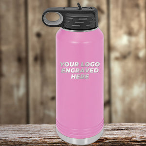 A Kodiak Coolers Engraved Custom Logo Drinkware, painted pink with a black lid, is placed on a wooden surface. The phrase "YOUR LOGO ENGRAVED HERE" is displayed on the front of the bottle, making it an ideal promotional gift. This product features special 72-hour sale pricing with single-side engraving included in the price.