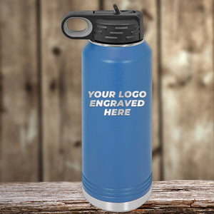 A blue stainless steel water bottle with a black cap from Kodiak Coolers sits on a wooden surface. The bottle, part of the "Engraved Custom Logo Drinkware" line, features "Your Logo Engraved Here" on its side and is an ideal promotional gift, especially during the SPECIAL 72 HOUR SALE PRICING event with single side engraving included in the price.